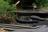 FILE PHOTO: People embrace as they stand near damage to a road, after the heaviest rain to hit the Atlantic Canadian province of Nova Scotia in more than 50 years triggered floods, in Ellershouse, West Hants Regional Municipality, Nova Scotia, Canada July 23, 2023. REUTERS/John Morris/File Photo