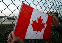 A Canada flag is held against a fence as the hearse carrying the casket of fallen soldier Pte.Terry Street, 24, drives past in Trenton, Ont., Tuesday April 8, 2008. Street was killed in Afghanistan on Friday by an improvised explosive device. THE CANADIAN PRESS/Sean Kilpatrick