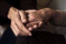 closeup of a young caucasian man holding the hand of an old caucasian woman with affection