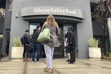 File - People stand outside of an entrance to Silicon Valley Bank in Santa Clara, Calif., Friday, March 10, 2023. The collapse of Silicon Valley Bank and Signature Bank, and the bailout of First Republic, was a jolt for small businesses of all stripes, spurring many to scrutinize their banking services and mull whether or not they should make changes to ensure their money is safe. (AP Photo/Jeff Chiu, File)