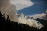 A helicopter carrying a water bucket flies past the Lytton Creek wildfire burning in the mountains near Lytton, B.C., on Sunday, Aug. 15, 2021. THE CANADIAN PRESS/Darryl Dyck