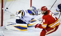 St. Louis Blues goalie Jordan Binnington, left, lets in a goal from Calgary Flames' Christopher Tanev during first period NHL hockey action in Calgary, Alta., Monday, Jan. 24, 2022. THE CANADIAN PRESS/Jeff McIntosh