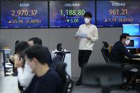 A currency trader passes by screens showing the Korea Composite Stock Price Index (KOSPI. 2021. Asian shares were mostly higher on Thursday, tracking an overnight rally on Wall Street as investors sought out bargains, including technology stocks. (AP Photo/Ahn Young-joon)