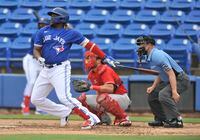 Philadelphia Phillies catcher Jeff Mathis, center, looks on as Toronto Blue Jays’ Vladimir Guerrero Jr. hits a single during the first inning of a spring training baseball game in Dunedin, Fla., Saturday, March 6, 2021. THE CANADIAN PRESS/Steve Nesius