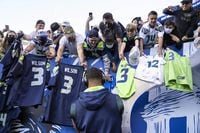Seattle Seahawks quarterback Russell Wilson signs autographs for fans before an NFL football game against the Los Angeles Chargers, Saturday, Aug. 28, 2021, in Seattle. (AP Photo/Stephen Brashear)