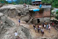 Residents and rescue workers inspect the area outside a house damaged by a landslide and the swell of the Thado-Koshi river due to heavy rains in Jambu village of Sindhupalchok district, some 80 kms northeast of Kathmandu, Nepal on July 9, 2020.