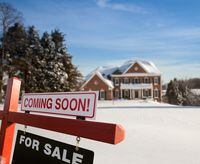 For Sale and Coming Soon realtor sign in front of large brick single family house in expansive snow cover yard in mid winter
