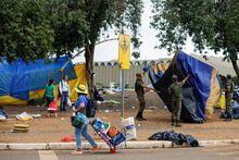 Supporters of Brazil's former President Jair Bolsonaro leave a camp outside the Army Headquarters as members of the military take down a tent, in Brasilia, Brazil.