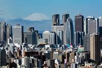 In this March 29, 2021, file photo, Mount Fuji appears behind the skyline of skyscrapers in the Shinjuku shopping and business district in Tokyo.