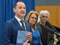 Quebec Finance Minister Eric Girard holds a copy of the 2023-24 budget speech as he responds to reporters at a news conference on March 20, 2023, in Quebec City. Quebec Families Minister Suzanne Roy, centre, and Dr. Gilles Julien look on. THE CANADIAN PRESS/Jacques Boissinot