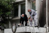 Workers fix the damage at the Cuban Embassy following an overnight petrol bomb attack, in Paris, on July 27.