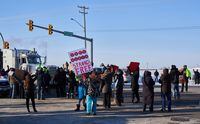 Protesters of COVID-19 restrictions, and supporters of Canadian truck drivers protesting the COVID-19 vaccine mandate cheer on a convoy of trucks on their way to Ottawa, on the Trans-Canada Highway west of Winnipeg, Manitoba, Tuesday January 25, 2022. THE CANADIAN PRESS/David Lipnowski