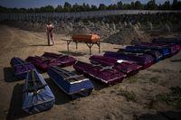 A priest blesses coffins with unidentified civilian bodies, who died on the territory of the Bucha community during the Russian occupation period in February-March 2022, during a funeral in Bucha, near Kyiv, Ukraine, on Friday, Sept. 2, 2022. (AP Photo/Emilio Morenatti)