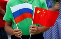 FILE PHOTO: A child holds the national flags of Russia and China prior to a welcoming ceremony for Russian President Vladimir Putin outside the Great Hall of the People in Beijing, China, June 25, 2016.   REUTERS/Kim Kyung-Hoon