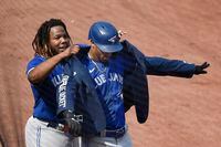 Toronto Blue Jays' Vladimir Guerrero Jr. puts the blue jacket on Lourdes Gurriel Jr. after Gurriel hit his second home run against the Baltimore Orioles, in the fifth inning of a baseball game, Sunday, Sept. 12, 2021, in Baltimore.