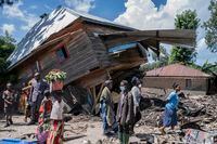 People walk next to a house destroyed by the floods in the village of Nyamukubi, South Kivu province, in Congo, Saturday, May 6, 2023.  The death toll from flash floods and landslides in eastern Congo has risen according to the governor and authorities in the country's South Kivu province. (AP Photo/Moses Sawasawa)