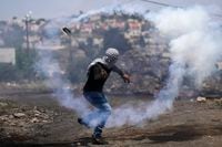 A Palestinian demonstrator hurls back a tear gas canister fired by Israeli forces during a protest against the West Bank Jewish settlements, in the West Bank village of Kafr Qaddum, Friday, May 20, 2022. (AP Photo/Majdi Mohammed)