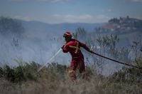 A firefighter directs water on a grass fire burning on an acreage behind a residential property in Kamloops, B.C., Monday, June 5, 2023. Climate experts say this summer of fires, floods and drought is far beyond the normal swings of Canadian weather. THE CANADIAN PRESS/Darryl Dyck