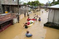 Residents give out free food as they wade through a flooded street in their village from Typhoon Noru in San Miguel town, Bulacan province, Philippines, Monday, Sept. 26, 2022. Typhoon Noru blew out of the northern Philippines on Monday, leaving some people dead, causing floods and power outages and forcing officials to suspend classes and government work in the capital and outlying provinces. (AP Photo/Aaron Favila)