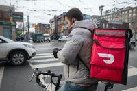 A DoorDash food delivery worker in downtown Toronto checks his mobile phone, on Jan 23 2020. Fred Lum/The Globe and Mail