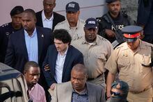 FILE - Sam Bankman-Fried, center left, founder of the failed cryptocurrency exchange FTX, is escorted out of Magistrate Court after a hearing in Nassau, Bahamas, Monday, Dec. 19, 2022. FTX was supposed to be the crown jewel of the Bahamian government's push to be the global destination for all things crypto, after years of having an economy overly reliant on tourism and banking. (AP Photo/Rebecca Blackwell, File)