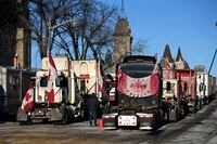 A person walks among trucks as Wellington Street is lined with trucks once again after city officials negotiated to move some trucks towards Parliament and away from downtown residences, on the 18th day of a protest against COVID-19 measures that has grown into a broader anti-government protest, in Ottawa, on Monday, Feb. 14, 2022. THE CANADIAN PRESS/Justin Tang