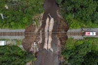 Workers with CN Rail assess the damage to a washed-out rail line outside of Truro, N.S. on Sunday, July 23, 2023. A long procession of intense thunderstorms dumped record amounts of rain across a wide swath of Nova Scotia, causing flash flooding, road washouts and power outages. THE CANADIAN PRESS/Darren Calabrese