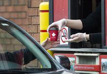 A Tim Hortons employee hands out coffee from a drive-through window to a customer in Mississauga, Ont., on Tuesday, March 17, 2020. The new executive chairman of Restaurant Brands International Inc. has laid out a sweeping vision for the fast-food giant's four chains, with plans to borrow from his winning playbook as CEO of Domino's Pizza. THE CANADIAN PRESS/Nathan Denette
