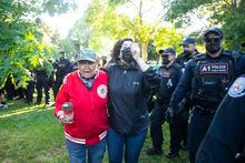 An Indigenous Elder, residential school survivor and 60's scoop survivor who identifies as "Redstone woman that walks with fire" (left) is removed from a sacred fire area by police during an eviction process at a homeless encampment in Toronto on Tuesday, June 22, 2021. THE CANADIAN PRESS/Chris Young