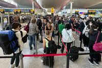 FILE - Travellers queue at security at Heathrow Airport in London, Wednesday, June 22, 2022. London’s Heathrow Airport  apologized Monday, July 11, 2022 to passengers whose travels have been disrupted by staff shortages. The airport warned that it may ask airlines to cut more flights from their summer schedules to reduce the strain if the chaos persists. (AP Photo/Frank Augstein, File)