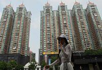 (FILES) This file photo taken on September 17, 2021 shows a woman walking past a housing complex by Chinese property developer Evergrande in Guangzhou, China's southern Guangdong province. - Debt-crippled Chinese property giant Evergande has defaulted for the first time, Fitch Ratings agency said on December 9, 2021, as authorities scrambled to avoid contagion throughout the world's second biggest economy. (Photo by Noel Celis / AFP) (Photo by NOEL CELIS/AFP via Getty Images)