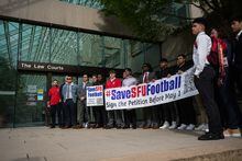 Simon Fraser University football team players hold a banner after attending a hearing at B.C. Supreme Court, in Vancouver, on Monday, May 1, 2023. The lawyer representing players and alumni of Simon Fraser UniversityÕs football team asked a judge to grant an injunction that would require the university to attempt to bring back the axed program. THE CANADIAN PRESS/Darryl Dyck