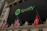 FILE PHOTO: The Spotify logo hangs on the facade of the New York Stock Exchange with U.S. and a Swiss flag as the company lists its stock with a direct listing in New York, U.S., April 3, 2018.  REUTERS/Lucas Jackson