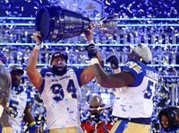 HAMILTON, ON - DECEMBER 12:  Jackson Jeffcoat #94 and Jermarcus Hardrick #51 of the Winnipeg Blue Bombers celebrate victory with the Grey Cup following the 108th Grey Cup CFL Championship Game against the Hamilton Tiger-Cats at Tim Hortons Field on December 12, 2021 in Hamilton, Ontario, Canada.  (Photo by Vaughn Ridley/Getty Images)