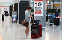 FILE PHOTO: A passenger stands next to a COVID-19 testing centre sign in the International arrivals area of Terminal 5 in London's Heathrow Airport, Britain, August 2, 2021.  REUTERS/Peter Nicholls