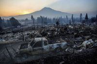 The sun rises over Mt. Shasta and homes destroyed by the Mill Fire on Saturday, Sept. 3, 2022, in Weed, Calif. (AP Photo/Noah Berger)
