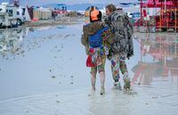 Dub Kitty and Ben Joos, of Idaho and Nevada, walk through the mud at Burning Man after a night of dancing with friends in Black Rock City, in the Nevada desert, after a rainstorm turned the site into mud September 2, 2023.  Trevor Hughes/USA TODAY NETWORK via REUTERS  NO RESALES. NO ARCHIVES.