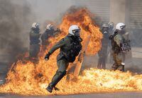 Protesters throw a petrol bomb at riot police during a protest in Athens, Greece.