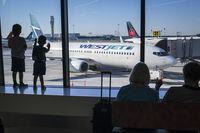 Young boys look out at Air Canada and WestJet planes at Calgary International Airport in Calgary, Alta., Wednesday, Aug. 31, 2022. THE CANADIAN PRESS/Jeff McIntosh