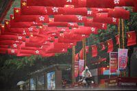 A cyclist rides in the rain under Chinese and Hong Kong flags decorating a street, before the 25th anniversary of the former British colony's handover to Chinese rule, in Hong Kong, China June 30, 2022. REUTERS/Paul Yeung