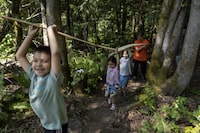 Paulina Taekema, Indigenous culture student support worker, rear, helps grade 1 and kindergarten students with carrying a cedar strip near Qwam Qwum Stuwixwulh School in Nanaimo, British Columbia, Thursday, May 18, 2023. Rafal Gerszak/The Globe and Mail 