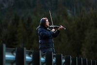 Carol Love plays "Tennessee Whiskey" on her violin at a todal lagoon near Zeballos, B.C., on Wednesday, April 17, 2024. The Nanaimo, B.C., woman says she is serenading a killer whale calf, hoping to entice the orca to leave the remote lagoon where she has been trapped alone for almost four weeks. THE CANADIAN PRESS/Chad Hipolito 