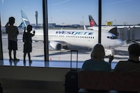 Young boys look out at Air Canada and WestJet planes at Calgary International Airport in Calgary, Alta., Wednesday, Aug. 31, 2022. THE CANADIAN PRESS/Jeff McIntosh