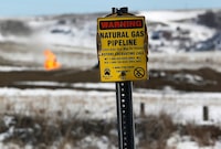 FILE PHOTO: A warning sign for a natural gas pipeline is seen in front of natural gas flares at an oil pump site outside of Williston, North Dakota March 11, 2013.  REUTERS/Shannon Stapleton/File Photo