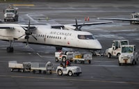A worker drives pass an Air Canada aircraft parked at a gate at Vancouver International Airport after operations returned to normal after last week's snowstorm, in Richmond, B.C., on Monday, December 26, 2022. THE CANADIAN PRESS/Darryl Dyck