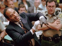 FILE - In this June 15, 1995 file photo, O.J. Simpson, left, grimaces as he tries on one of the leather gloves prosecutors say he wore the night his ex-wife Nicole Brown Simpson and Ron Goldman were murdered in a Los Angeles courtroom. Simpson, the decorated football superstar and Hollywood actor who was acquitted of charges he killed his former wife and her friend but later found liable in a separate civil trial, has died. He was 76. (Sam Mircovich/Pool Photo via AP, File)