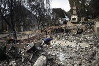 FILE - Roger Kelton searches through the remains of his mother-in-law's home leveled by the Woolsey fire, Nov. 13, 2018, in the southern California city of Agoura Hills. Southern California Edison will pay $80 million to settle claims connected to a massive wildfire that destroyed more than a thousand homes and other structures in 2017, federal prosecutors said Monday, Feb. 26, 2024. (AP Photo/Jae C. Hong, File)