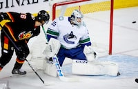 Vancouver Canucks goalie Thatcher Demko, right, blocks the net as Calgary Flames forward Martin Pospisil deflects the puck wide during first period NHL hockey action in Calgary, Saturday, Dec. 2, 2023.THE CANADIAN PRESS/Jeff McIntosh