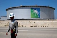 FILE PHOTO: An Aramco employee walks near an oil tank at Saudi Aramco's Ras Tanura oil refinery and oil terminal in Saudi Arabia May 21, 2018. REUTERS/Ahmed Jadallah/File Photo