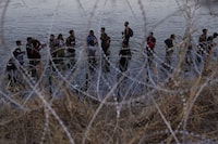 FILE - Migrants wait to climb over concertina wire after they crossed the Rio Grande and entered the U.S. from Mexico, Sept. 23, 2023, in Eagle Pass, Texas. A divided Supreme Court on Tuesday, March 19, 2024, lifted a stay on a Texas law that gives police broad powers to arrest migrants suspected of crossing the border illegally, while a legal battle over immigration authority plays out. (AP Photo/Eric Gay, File)
